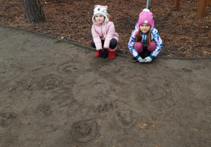Dziewczynki rysują Układ Słoneczny w ogrodzie przedszkolnym